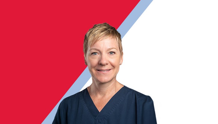 Smiling photo of Amy, a woman with short blonde hair wearing navy blue scrubs, looking directly at the camera.